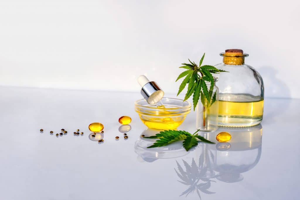 Glass bottle with CBD oil, THC tincture and hemp leaves on white background lab